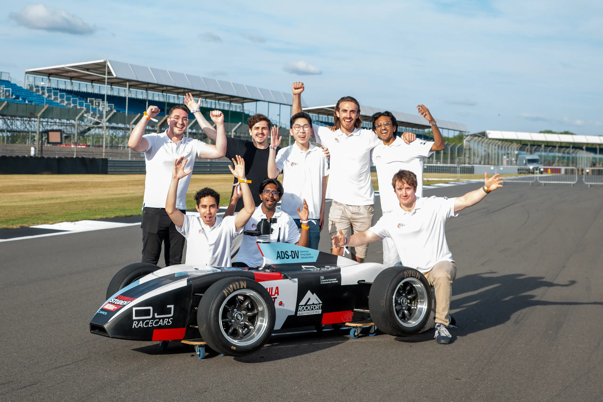 Tom Lam and the Bristol Formula Student AI team celebrating with their autonomous race car at Silverstone